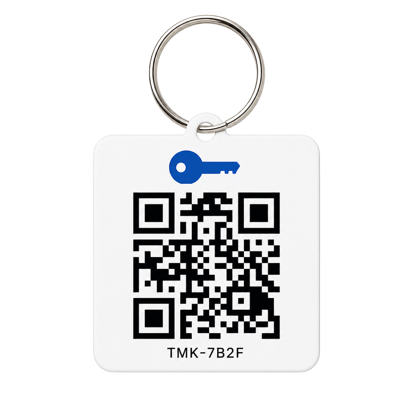 A printed Track My Keys QR key tag on a split ring, showing a QR code and the set code TMK-7B2F.