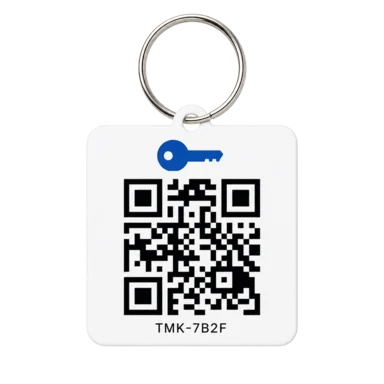 A printed Track My Keys QR key tag on a split ring, showing a QR code and the set code TMK-7B2F.